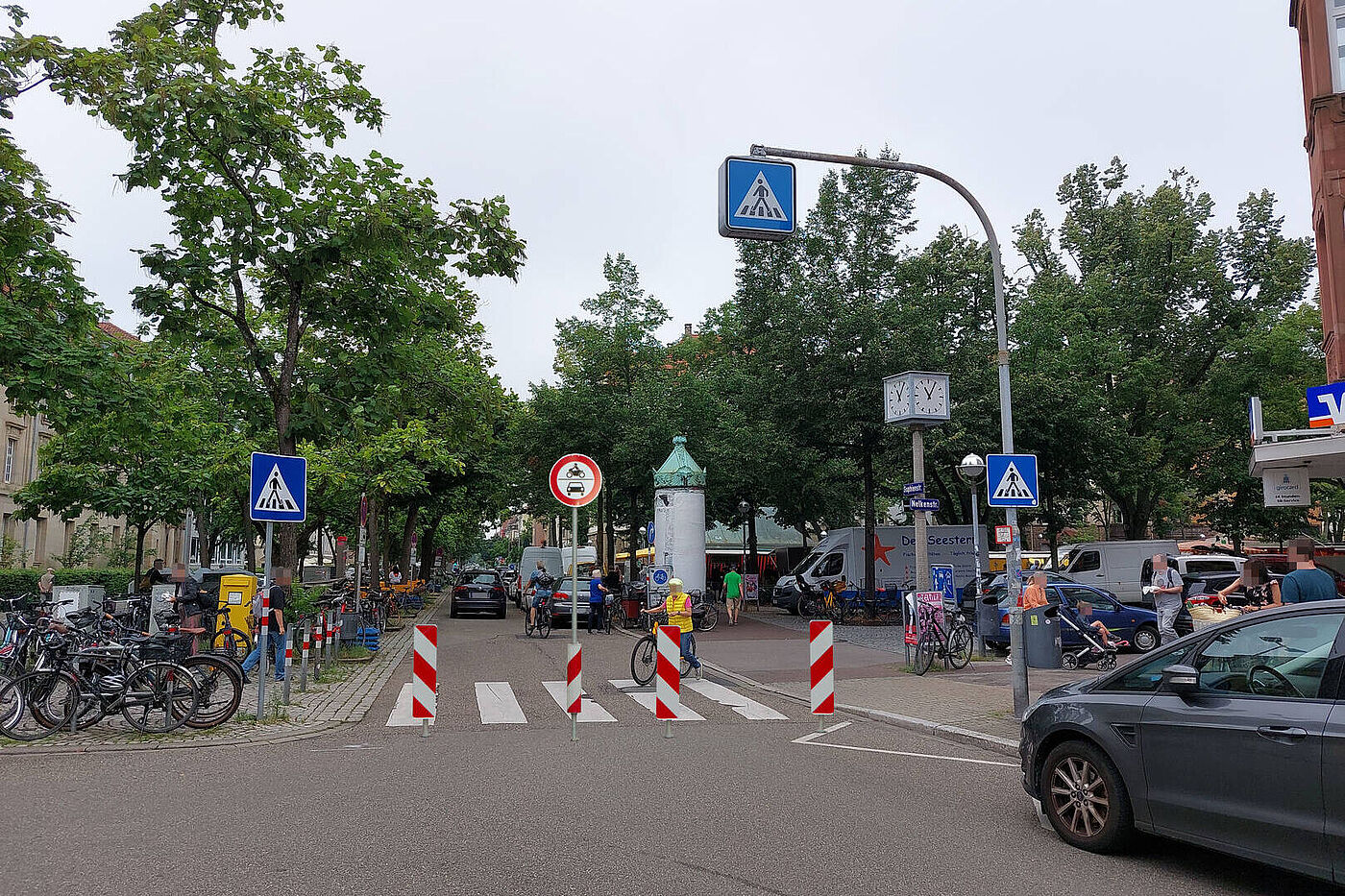 Fotomontage eines möglichen Pollers auf der Sophienstraße zwischen Gabelsbergerstraße und Nelkenstraße. Das Bild zeigt die nördliche Fahrbahn der Sophienstraße mit Blick Richtung Westen auf den Zebrastreifen zwischen den beiden vorgenannten Querstraßen. Vor dem Zebrastreifen sind Poller und das Verkehrszeichen 260 (Durchfahrtsverbot für Kfz) platziert.